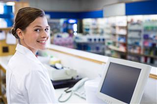Pharmacist Standing At Counter In Pharmacy