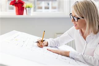 Woman Working On Architectural Blueprints