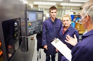 Engineer Teaching Apprentices To Use Computerized Lathe