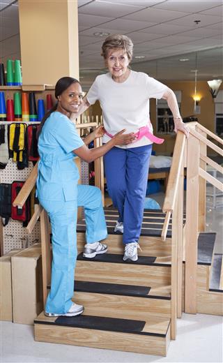 Therapist With Senior Woman Climbing Stairs