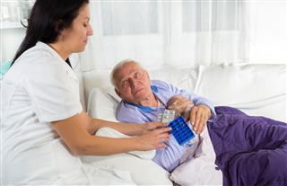 Nurse Helping Senior Man With Medication