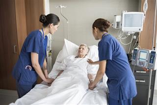 Nurses Reassuring Senior Woman In Bed
