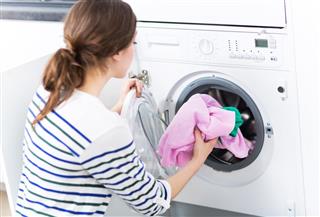 Woman Putting Laundry Into Washing Machine