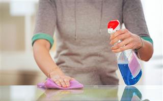 Woman Cleaning Glass Table With Spray