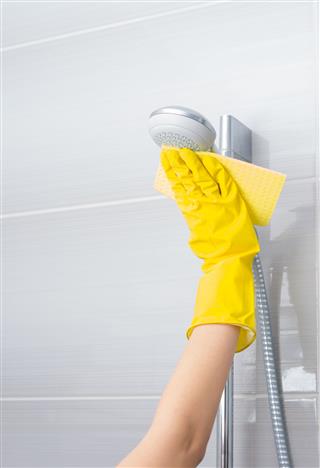 Woman Cleaning A Shower Fixture