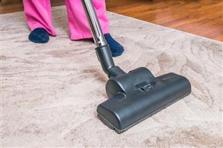 Woman Vacuuming Carpet With Vacuum Cleaner