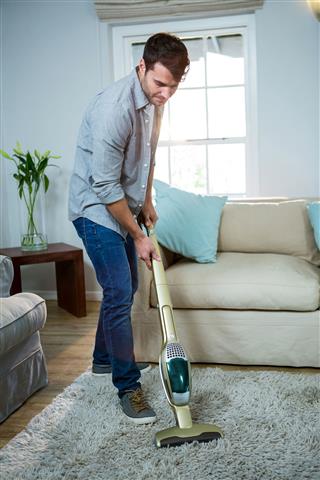 Man Cleaning Carpet With Vacuum Cleaner