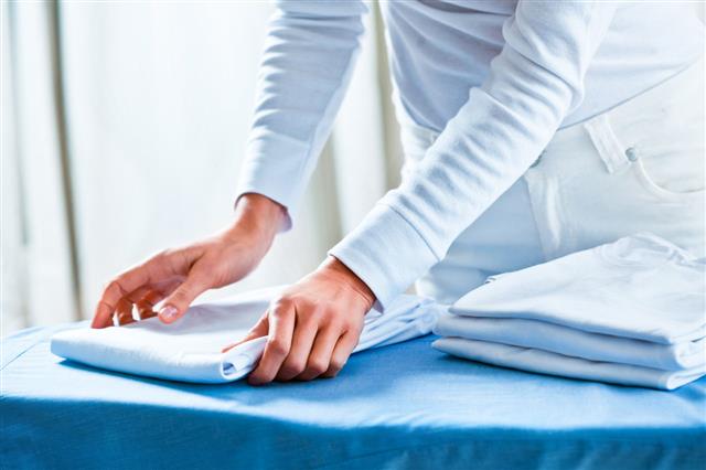 Woman Stacking Ironed Folded Shirts