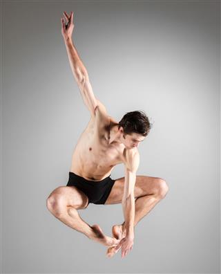 The Young Attractive Modern Ballet Dancer Jumping On White Background