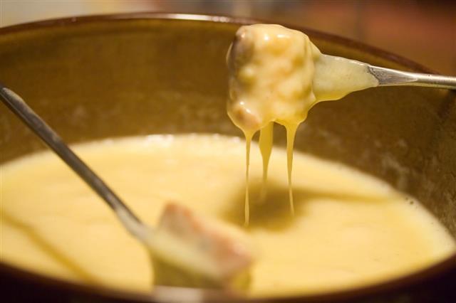 Forks Dipping Into A Fondue Pot