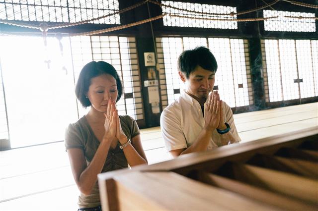 Japanese Couple Praying In Temple