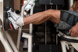 Bodybuilder Performing Seated Leg Press At Gym