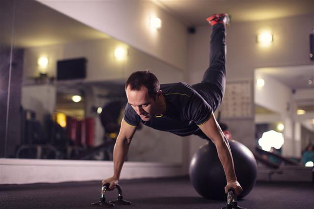 Man Exercising Weight Training In Gym