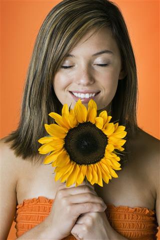 Smiling Young Woman Smelling Sunflower