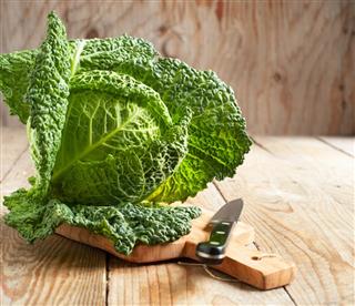 Savoy cabbage on wooden chopping board