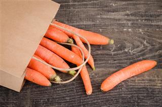 Bunch of fresh carrots in a brown paper bag