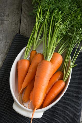 Fresh carrots with green tops on wooden table