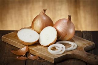 Gold onions on a wooden cutting board