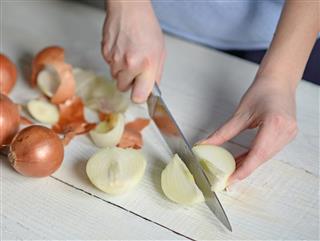 Woman hand cut fresh onion on white table