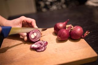 Cutting onions with knife on cutting board