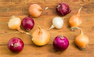Several onion bulbs different varieties on an old wooden surface