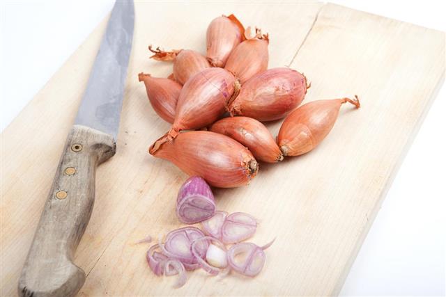 Raw shallots with old knife on wooden board