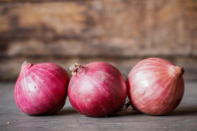 Close-up of fresh red onions on a wooden background