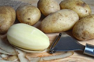 Peeling Potatoes On Wooden Board
