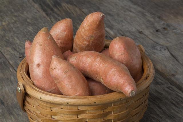 Sweet Potatoes in Basket on Wood Table