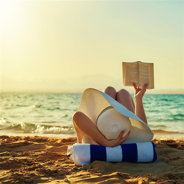 Woman Reading Book At Beach