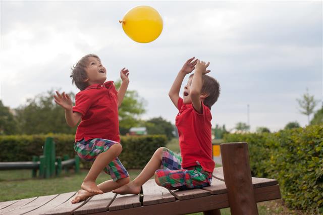 Two Boys Playing With Yellow Balloon