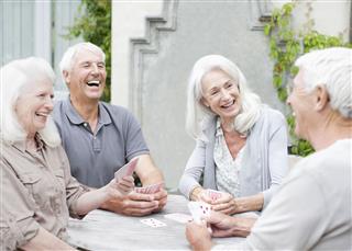 Senior Couples Playing Cards On Patio