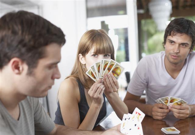 Three People Playing Cards At Table