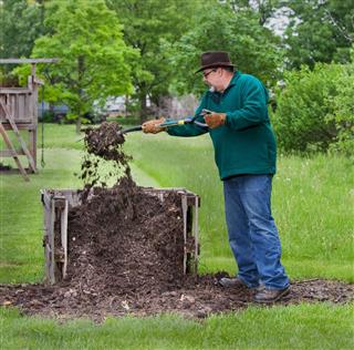 Man turning compost with pitchfork