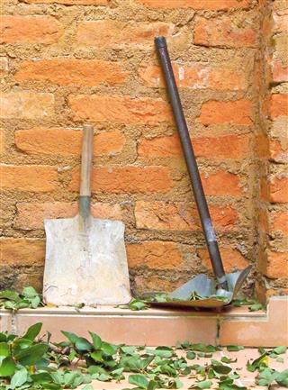 Shovels on a brick wall