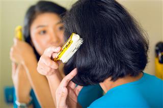 Woman Combing Hair In Bathroom