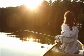 Girl Fishing From A Canoe At Sunrise