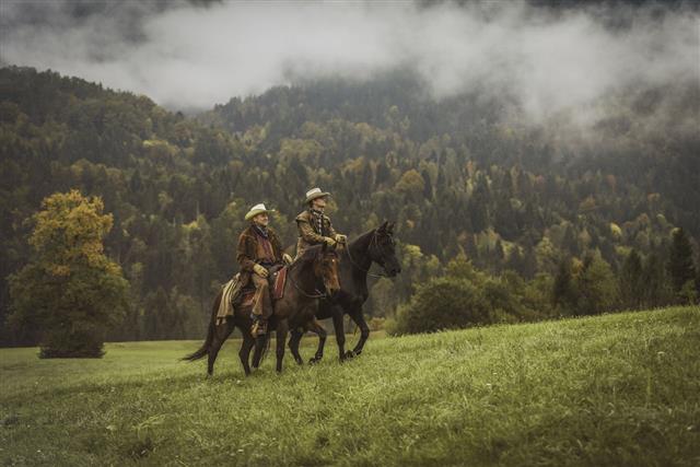 Cowboys Riding Across A Meadow