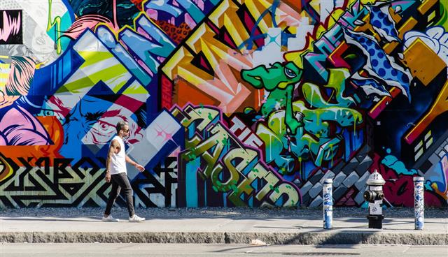 Male Walking Next To Wall Of Graffiti
