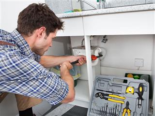 Plumber Fixing Sink In Kitchen