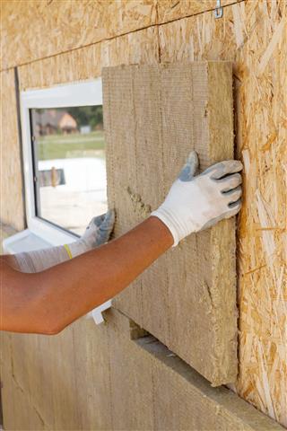 Worker Installing Insulation Material On Wall