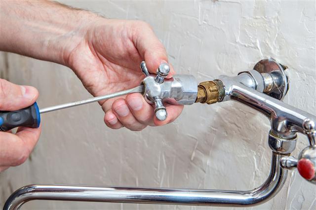 Plumber Unscrews Kitchen Faucet