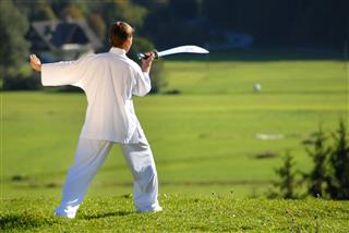 Tai Chi Exercise With Sword In Nature On Green Field