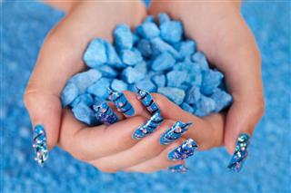 Hands holding pile of blue stones after manicure