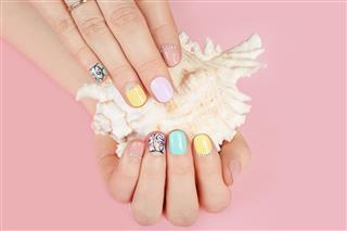 Hands with beautiful manicured nails and sea shell