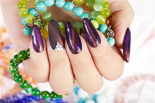 Hand with long artificial manicured nails holding bracelets