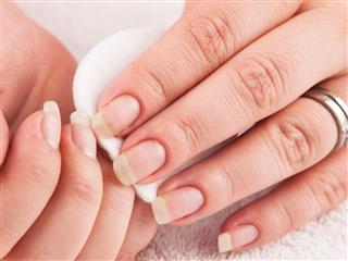 Woman using nail remover, making manicure herself