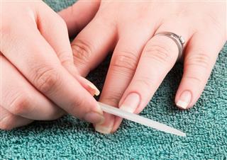 Woman making manicure herself, using nailfile