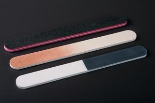 Three nail file with a different abrasive on dark background