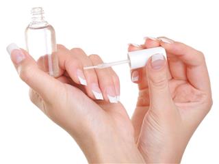 Woman applying clear nail vanish on her fingernails